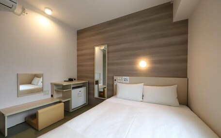 A hotel room with a bed, a bedside table, a mirror, a wardrobe, and a sign indicating Wi-Fi availability.