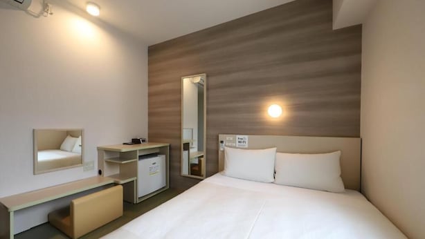 Hotelkamer met een bed, nachtkastje, spiegel, kledingkast en een bordje dat aangeeft dat wifi beschikbaar is.