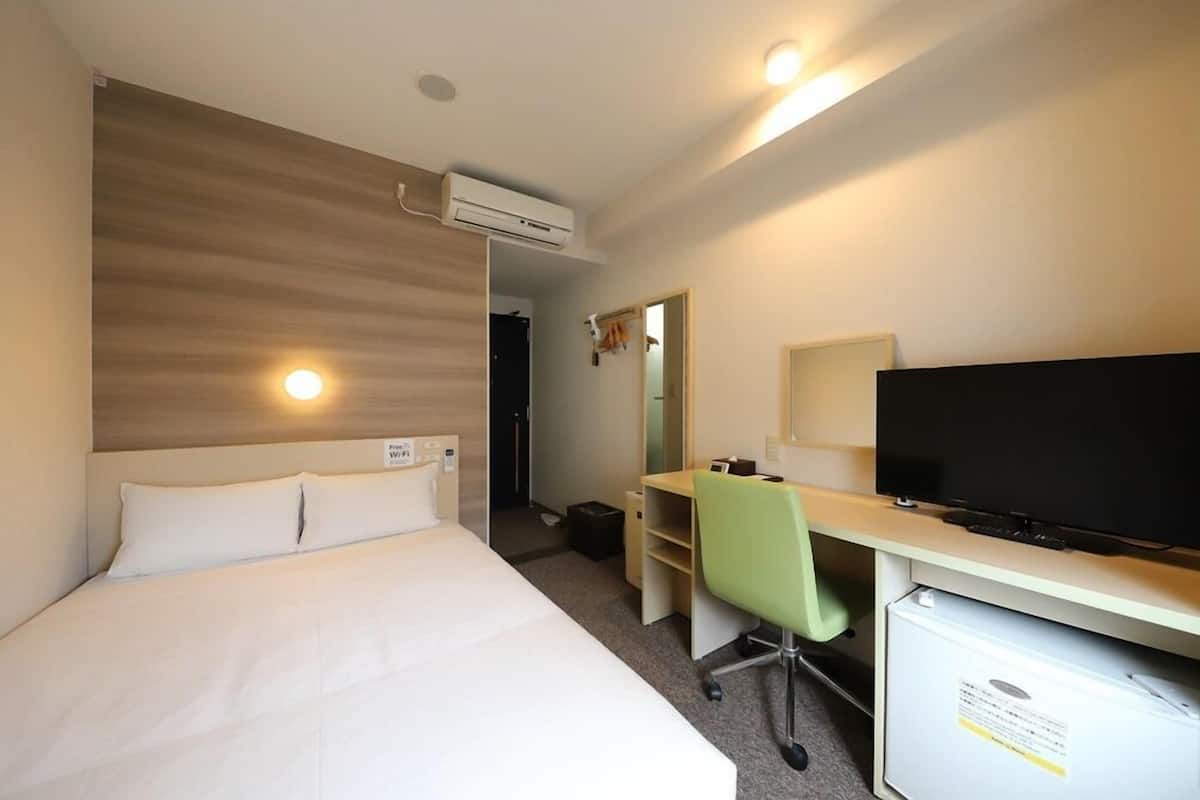 Une chambre d’hôtel équipée d’un lit, d’un bureau, d’une télévision et d’un appareil de climatisation.