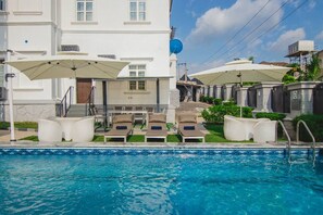 A swimming pool with lounge chairs and umbrellas, a white building with a staircase, and a satellite dish. - BON Hotel Asokoro Residence (Abuja)