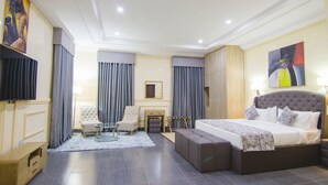 Una habitación de hotel moderna con una cama grande, una zona de estar con una silla y una mesa pequeña, un escritorio y un televisor.