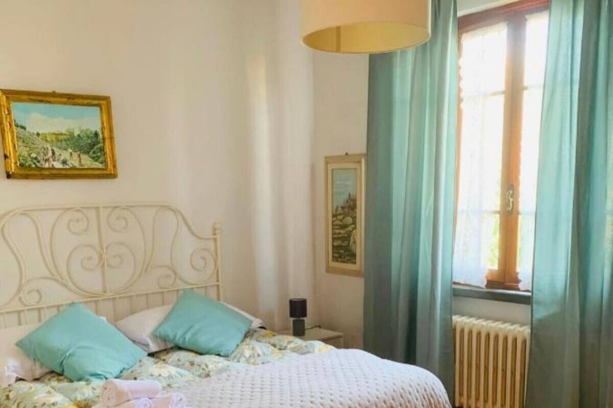 A bedroom with a bed, a nightstand, a lamp, and a window with curtains.