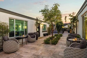 Un espace extérieur aménagé en terrasse, avec des sièges, un petit arbre et une vue sur un bâtiment en arrière-plan.
