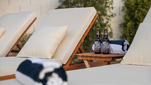 A lounge area with reclining chairs, a blanket, and two bottles of beer. - Montecito Luxe: 3-Villa Retreat w/ Pool Courtyard (Phoenix)