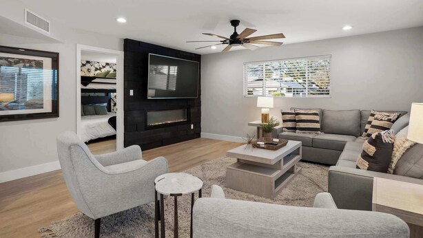 A modern living room with a flat-screen TV, a ceiling fan, a fireplace, and a sofa set. - Montecito Luxe: 3-Villa Retreat w/ Pool Courtyard (Phoenix)