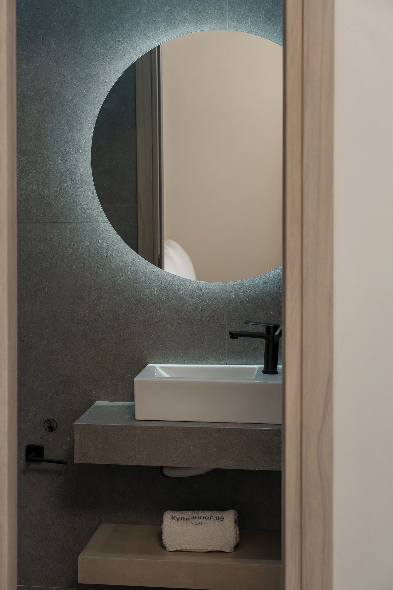 A bathroom with a round mirror, a white sink, and a towel rack.