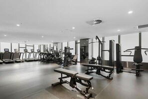 Une salle de sport moderne équipée de tapis de course, de vélos elliptiques et de matériel de musculation.