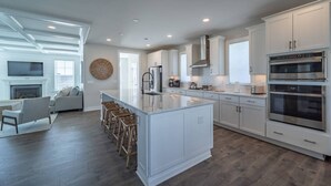 A modern kitchen with white cabinetry, a large island, and built-in appliances. - Coastal Comfort: 4BR 3BH House Pool & Rooftop Deck (Selbyville)