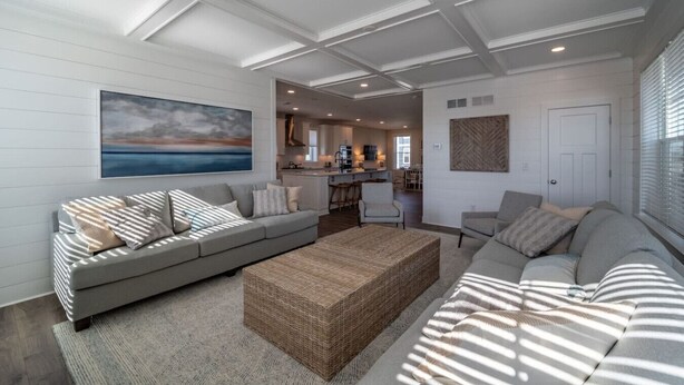 A spacious living area with a sofa set, a woven coffee table, and a painting on the wall. - Coastal Comfort: 4BR 3BH House Pool & Rooftop Deck (Selbyville)