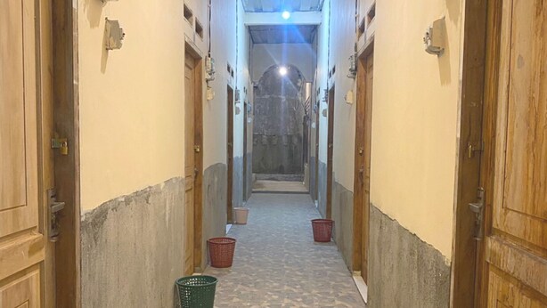 En hall med kakelgolv, trädörrar och korgar på golvet.