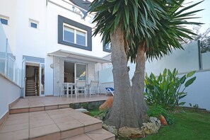A modern house with a patio, outdoor seating, and a palm tree.