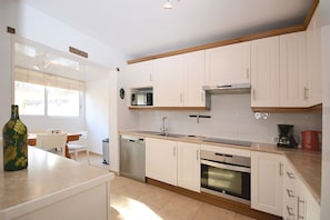 A modern kitchen with white cabinets, a microwave, a dishwasher, and an oven.