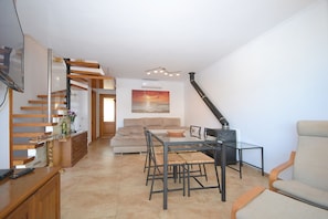 A modern living room with a dining area, a staircase, and a fireplace.