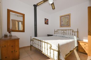 A bedroom with a bed, a wooden dresser, a mirror, and a painting on the wall.