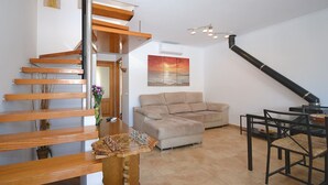 Ein modernes Interieur mit einer Holztreppe, einem beigefarbenen Sofa und einem Esstisch.
