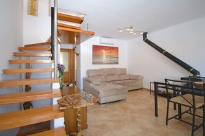 A modern interior with a wooden staircase, a beige sofa, and a dining table.