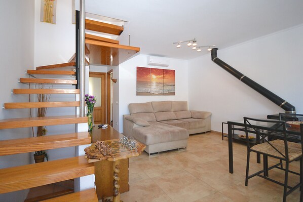 Un interior moderno con una escalera de madera, un sofá color beige y una mesa de comedor.