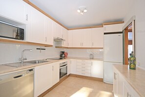 A modern kitchen with white cabinets, a stainless steel sink, a dishwasher, and a built-in oven. - Can Bennasar - Townhouse 400 meters from the sea in Mallorca (Can Picafort)