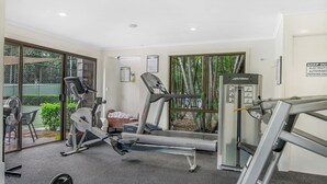 Un gimnasio con máquinas de cardio, equipo de levantamiento de pesas y una cinta de correr.