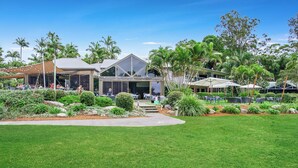 A resort with a large lawn, outdoor seating, and a building with a triangular roof. - Cuttlefish Cove - 2BR Resort Living by Diggers Beach (Coffs Harbour)