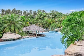 Une piscine entourée d’une végétation tropicale et agrémentée d’un petit kiosque.