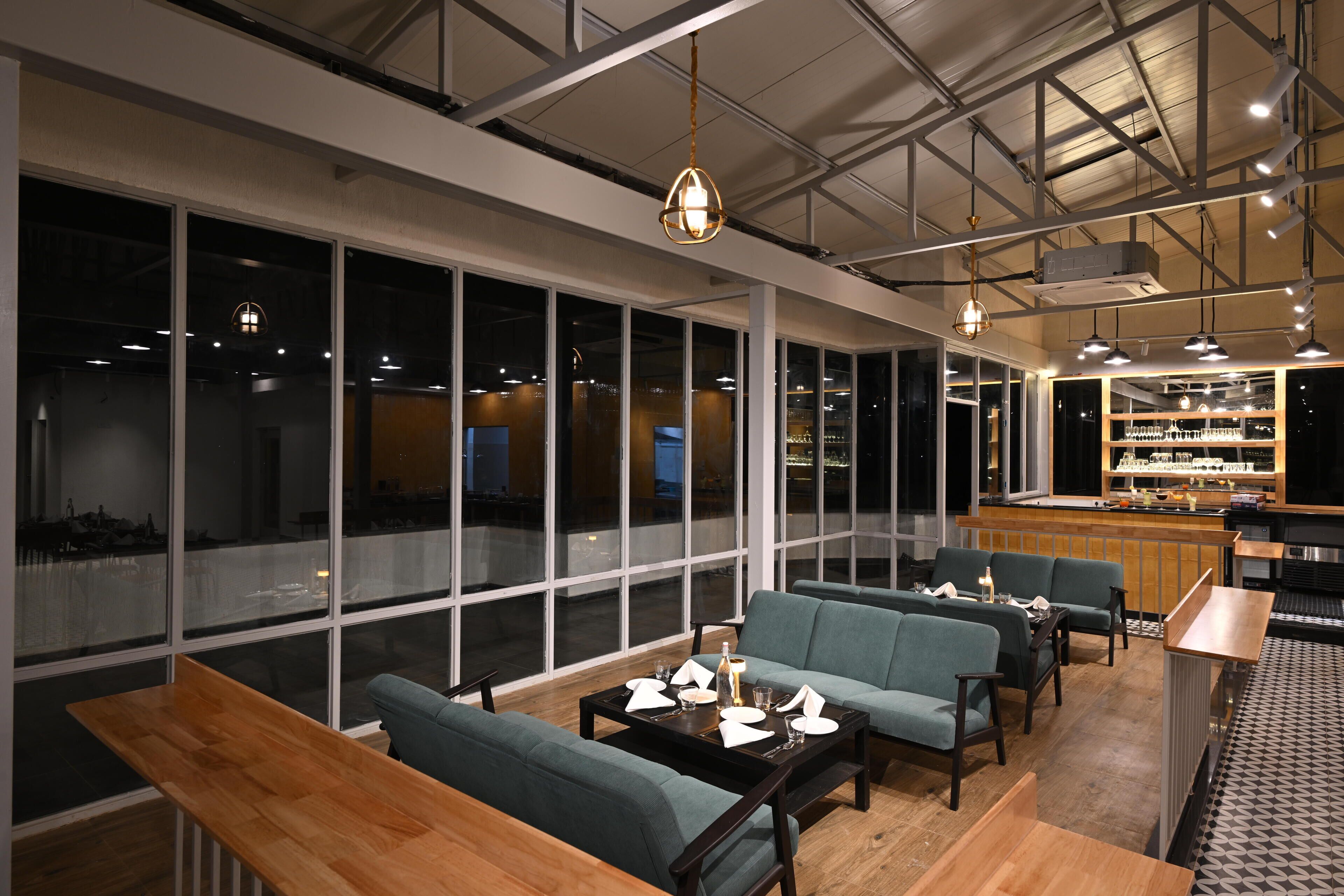 Uma área de estar moderna com assentos, um bar e amplas janelas com vista para a cidade.