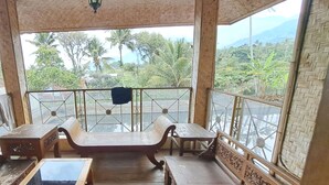 A wooden deck with a bench and table, surrounded by a railing with decorative elements. - OYO 93656 Villa Cassanova Syariah (Garut)