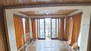 A room with a wooden floor, large windows with curtains, and a metal railing. - OYO 93656 Villa Cassanova Syariah (Garut)