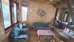 A cozy room with a wooden ceiling, a brick wall, a sofa, a table, and a fireplace. - OYO 93656 Villa Cassanova Syariah (Garut)