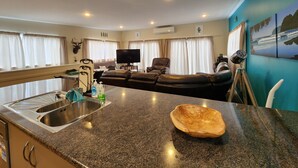 Ein modernes Wohnzimmer mit einem schwarzen Ledersofa, einem Flachbildfernseher und einer Essecke mit einer Granit Arbeitsplatte.