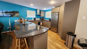 Eine moderne Küche mit einer Granit-Arbeitsplatte, Edelstahlgeräten und Holzboden.