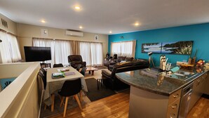 Ein modernes Wohnzimmer mit Essbereich, einer Küche mit Granitarbeitsplatte und einer blauen Akzentwand.