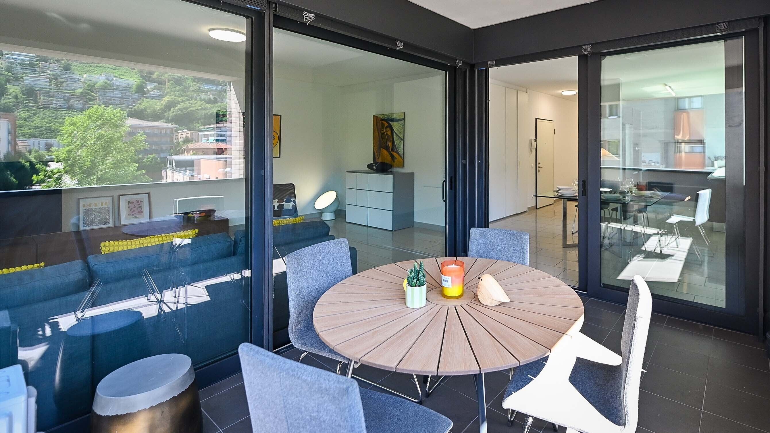 Un espace repas moderne avec une table ronde, des chaises bleues et une cloison en verre.