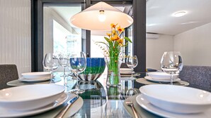 A dining table set with plates, glasses, and a vase with flowers. - Central Plaza Apartment 3 in Lugano (Lugano)