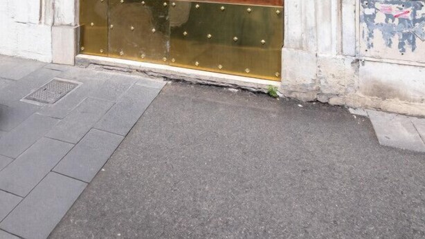 Une porte à deux battants en bois, surmontée d’une arche décorative en métal.