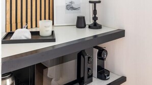 Une cuisine moderne avec un plan de travail noir, une machine à café et un tableau encadré accroché au mur.