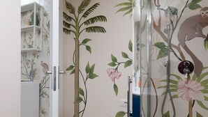 A bathroom with a shower, a toilet, and a sink. There is a door with a white frame and a glass shower enclosure. - Cozy Love Nest Steps from Colosseum (Roma)