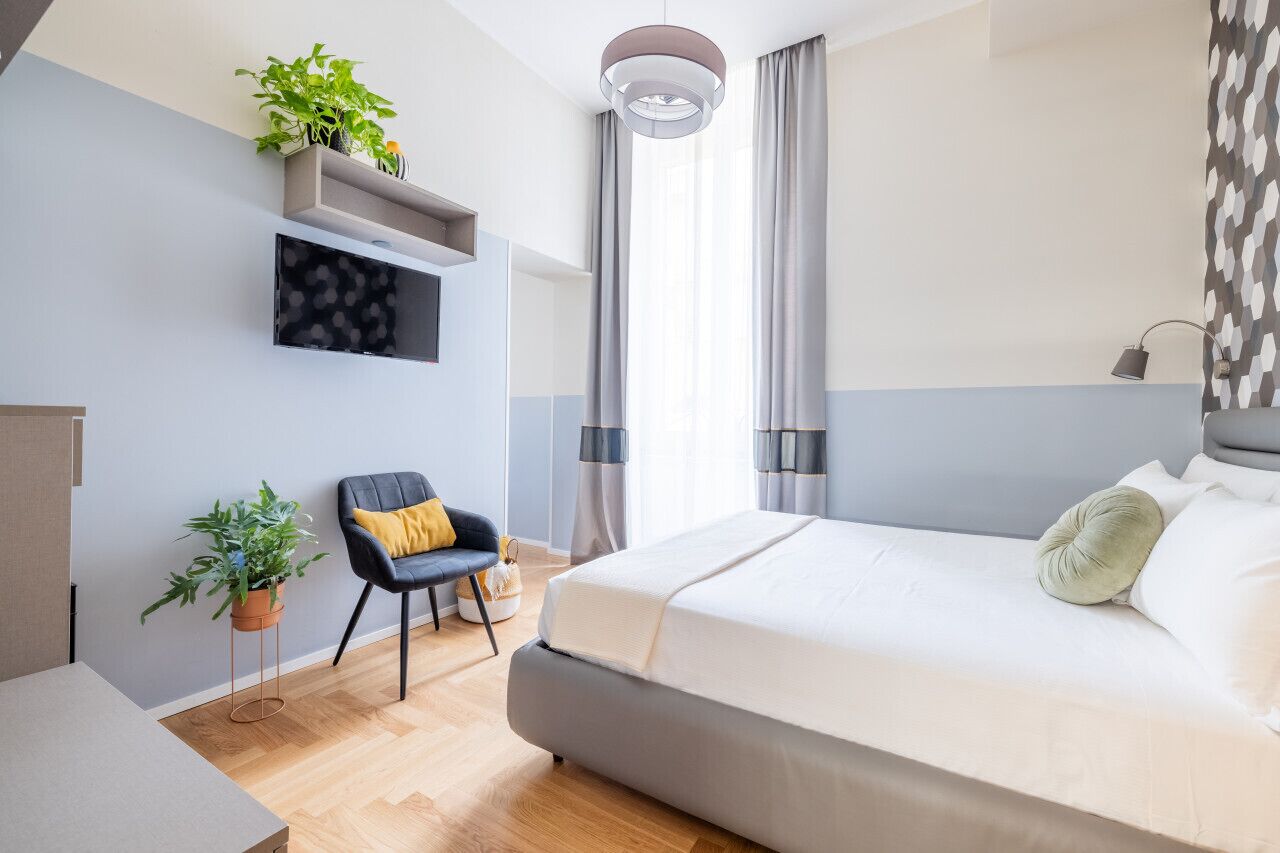 Une chambre à coucher moderne avec un lit, une chaise, un bureau et deux plantes en pot.