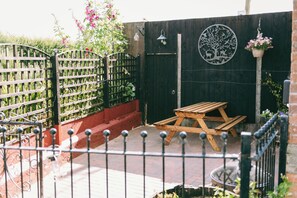 A wooden fence with a gate, a wooden table, and a hanging flower pot.