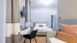 A compact hotel room with a bed, a desk, a chair, and a sofa. - Tiberia Room - Suites Romae Rex (Roma)
