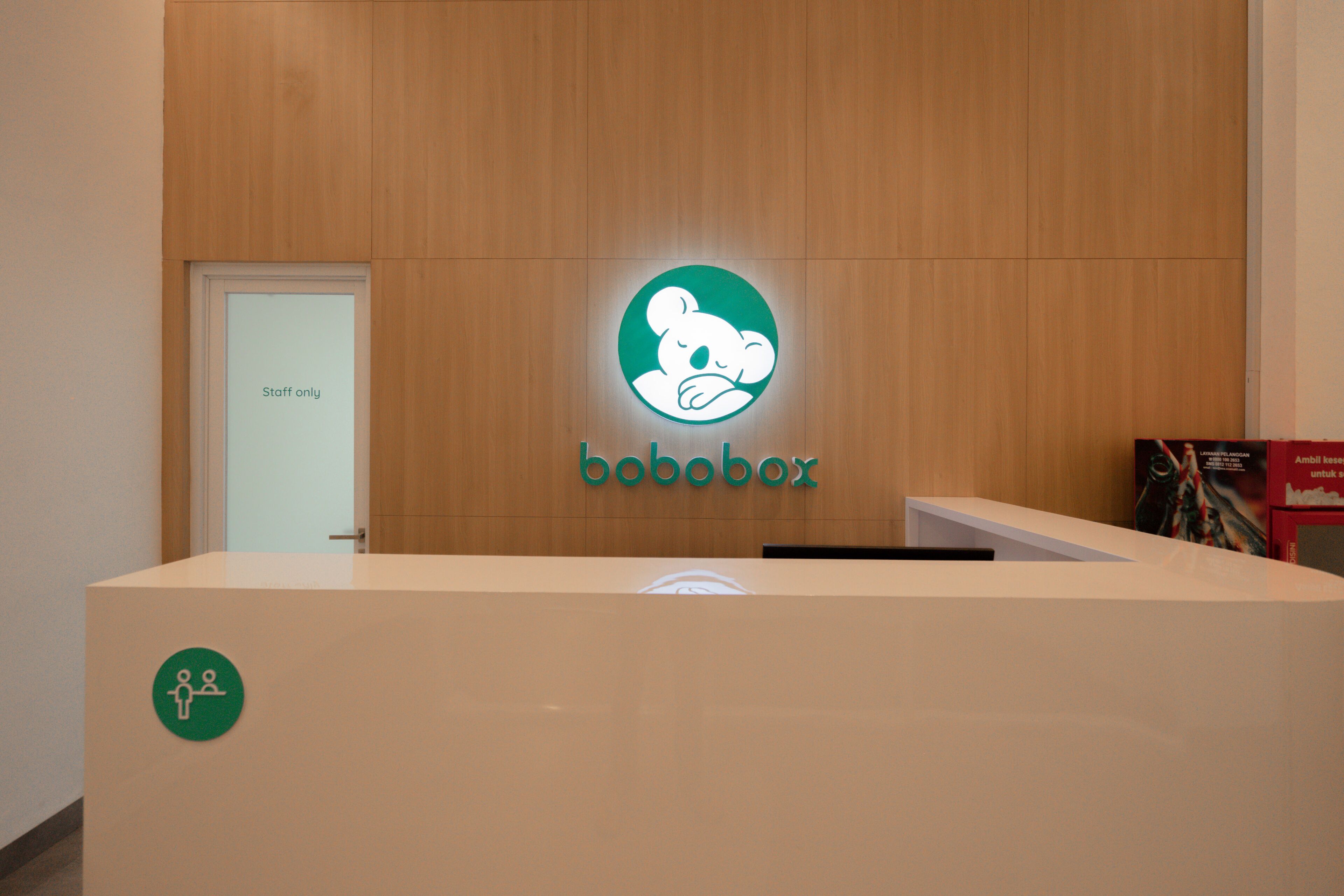 Ein Empfangstresen mit Holzpaneelen, dem 'bobobox'-Logo und einem Schild mit der Aufschrift 'Nur für Mitarbeiter'.