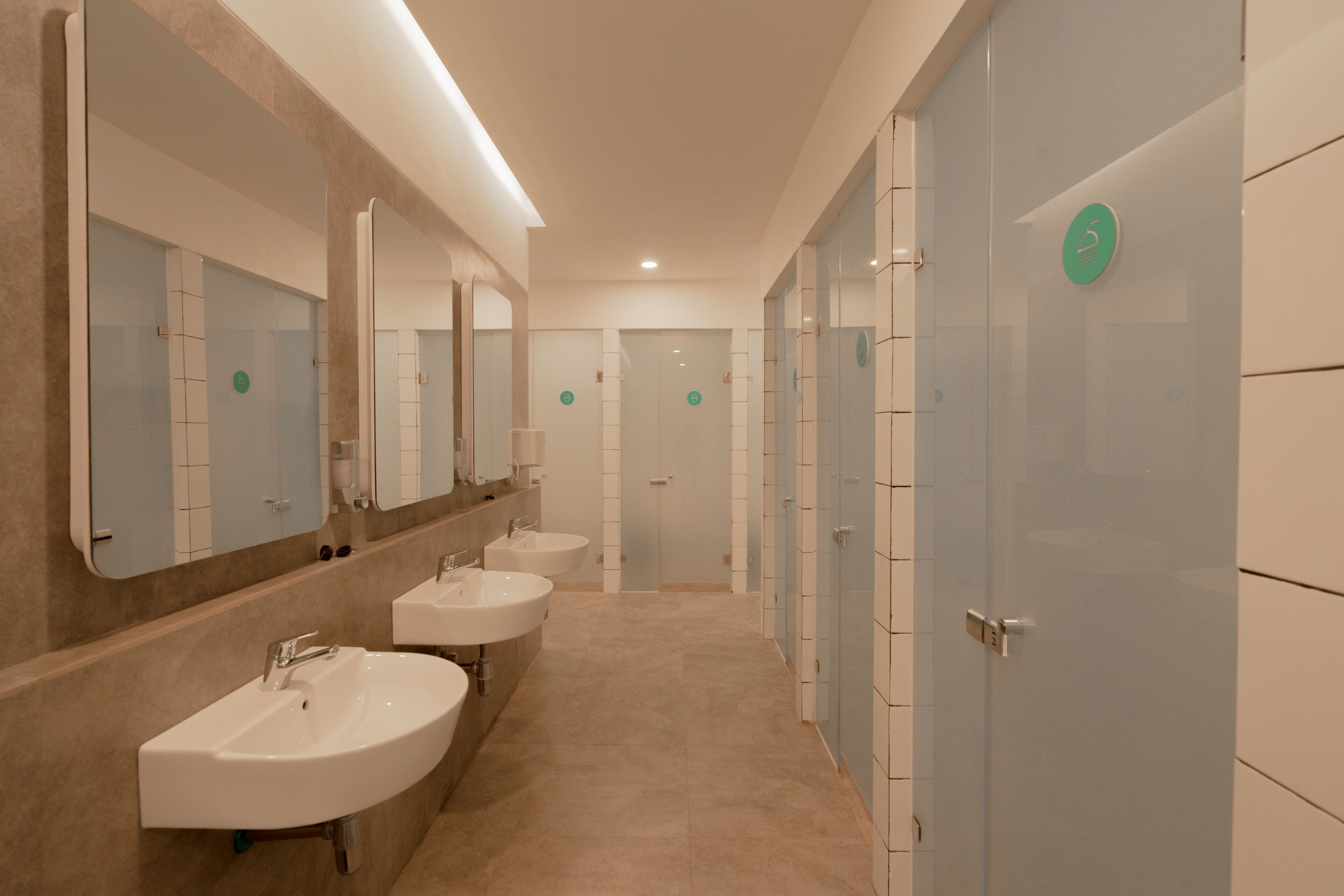 A modern bathroom with three sinks, large mirrors, and a tiled floor.