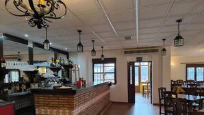 A restaurant interior with a brick counter, tiled floor, hanging lanterns, and a view through a window.