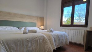 A hotel room with two beds, a window with a view, and a radiator.