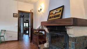 A living room with a stone fireplace, a wooden bench, and a wall-mounted light fixture.