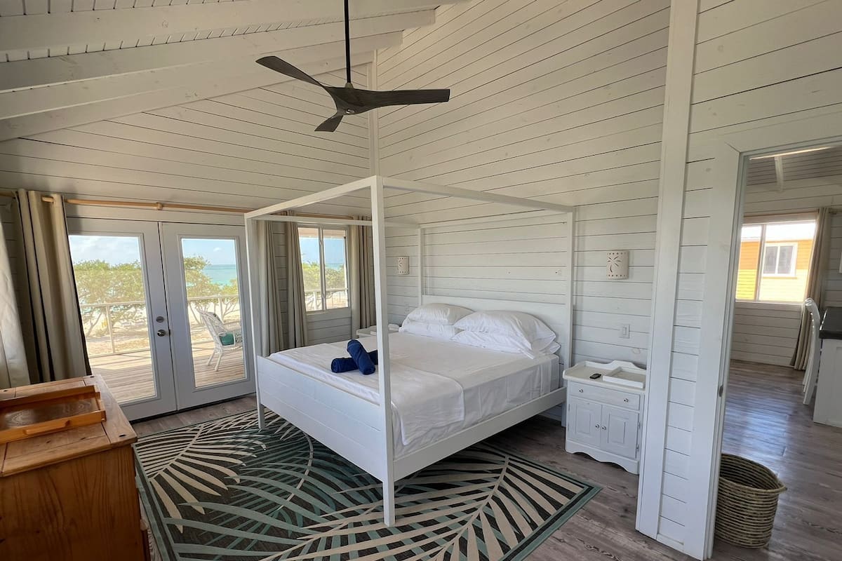 A four-poster bed with a canopy, a wooden nightstand, a small table, and a woven basket.