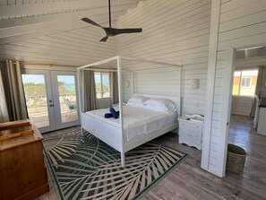 A four-poster bed with a canopy, a wooden nightstand, a small table, and a woven basket.
