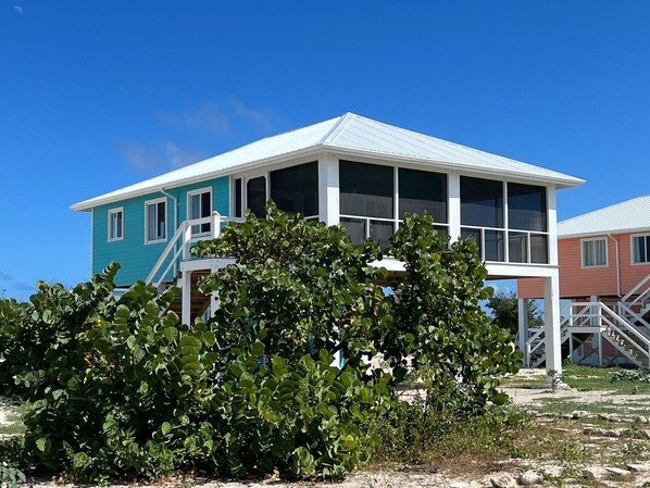 A two-story house with a white balcony and a large window. - Barbuda Cottages (Codrington)