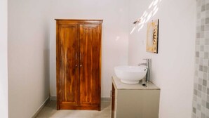 Une salle de bain avec un placard en bois, un lavabo blanc et une douche carrelée.