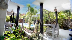 Une terrasse extérieure avec une piscine, entourée de plantes tropicales et de meubles en bois.